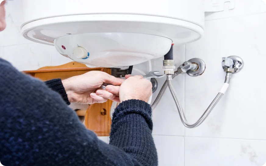 Técnico conectando la manguera flexible de un termo eléctrico durante una reparación en Barcelona