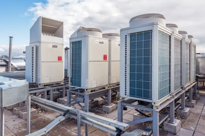 Técnicos expertos en climatización instalan equipos industriales en una azotea de Barcelona